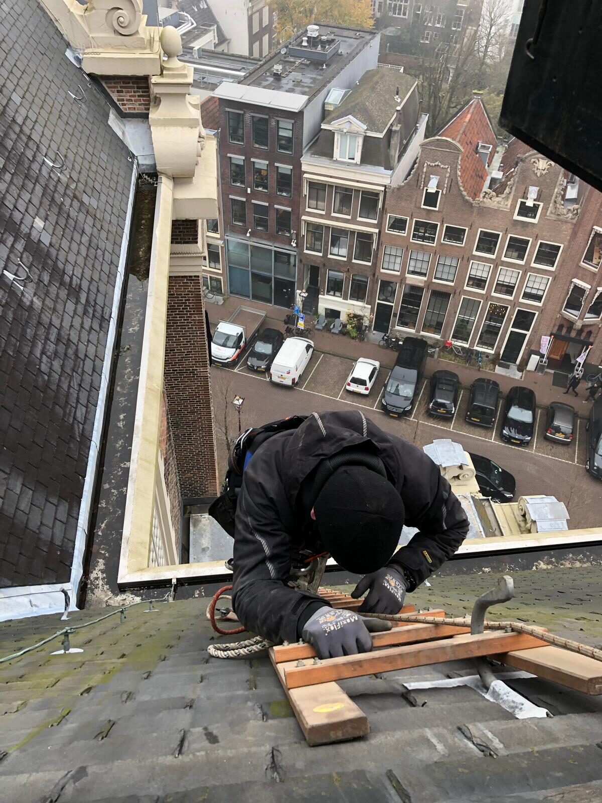 Vakman aan het werk op het dak van de Westerkerk, hoog boven de gracht